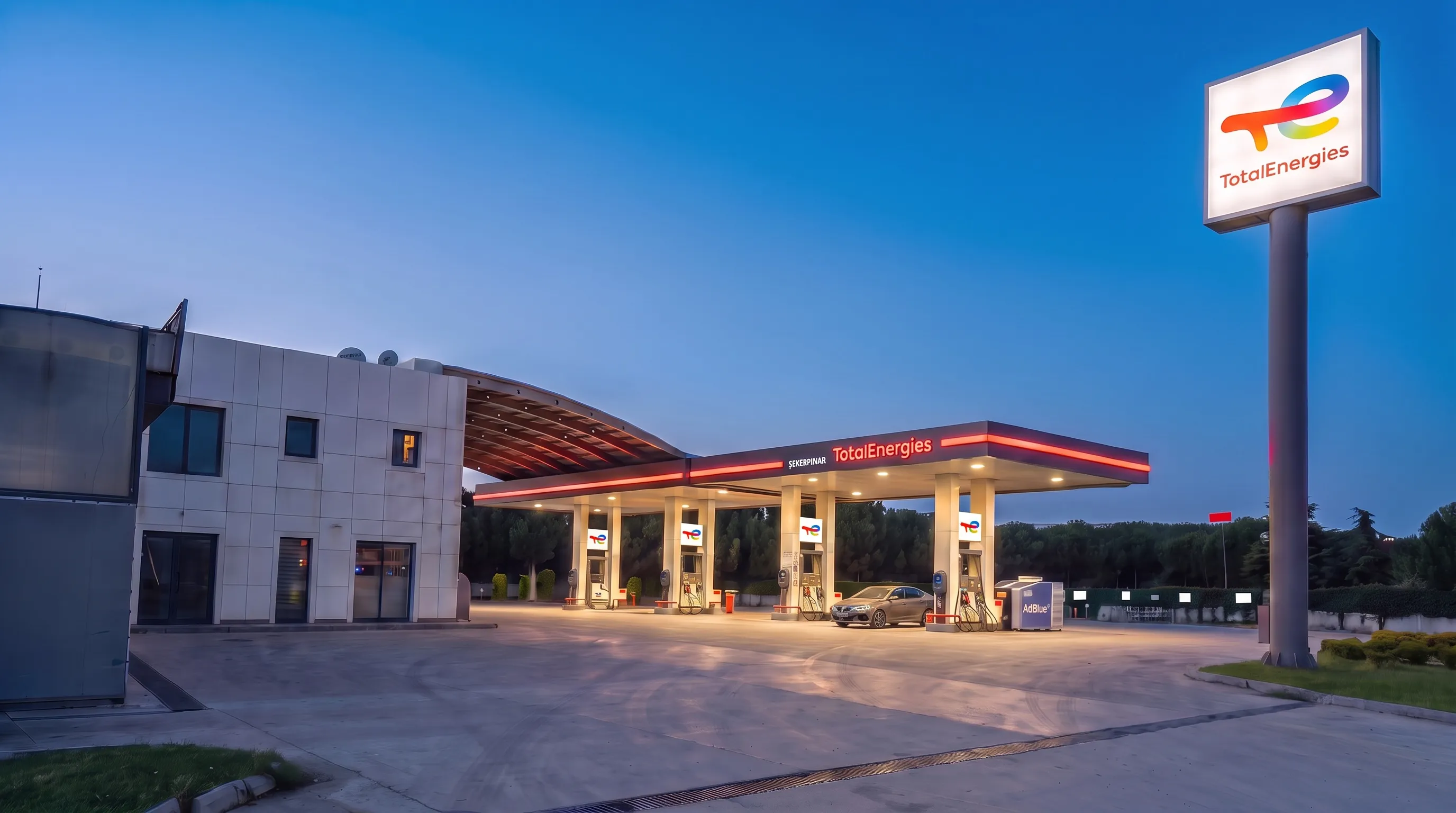 Mavi saatte TotalEnergies pilonu ve aydınlatılmış pompa kanopisi